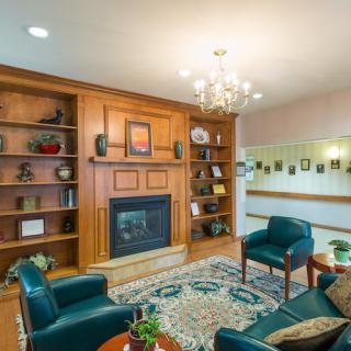 A cozy living room with a fireplace, bookshelves, and comfortable seating illuminated by a chandelier.