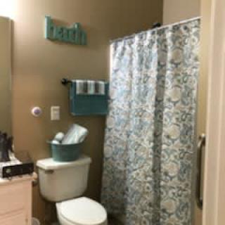 A neatly organized bathroom with a patterned shower curtain and teal accents.