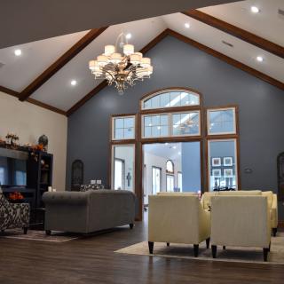A modern living room with a vaulted ceiling, featuring elegant furniture and a striking chandelier.
