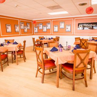 A cozy restaurant dining area featuring neatly arranged tables and an inviting orange color scheme.