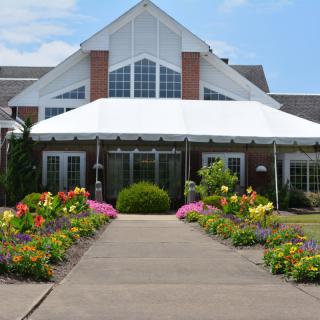 A beautiful garden pathway leading to a large building with a white awning.