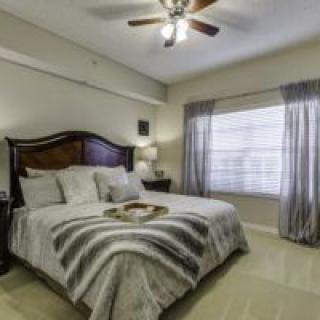 A cozy bedroom with a large bed, lamp, and window with curtains.