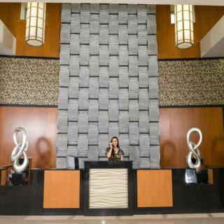 A modern hotel lobby with a reception desk and decorative sculptures.