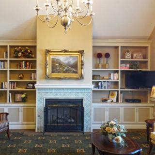 A cozy living room with a fireplace, bookshelves, and a chandelier.