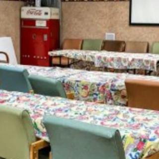 A cozy indoor cafe setting with colorful tablecloths on tables and a retro refrigerator in the background.