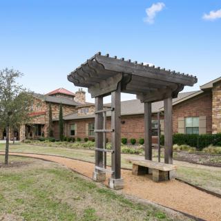 An outdoor view of a building with a pergola and landscaped pathway.