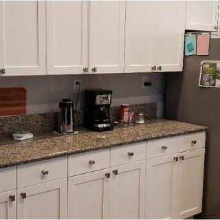 A kitchen with white cabinets, a granite countertop, and various appliances.