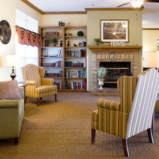A cozy living room with armchairs, a bookshelf, and a fireplace.