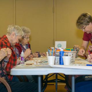 A group of people participating in an arts and crafts activity at a table indoors.