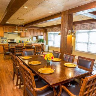 A spacious dining area with a large wooden table and chairs, adjacent to a modern kitchen.