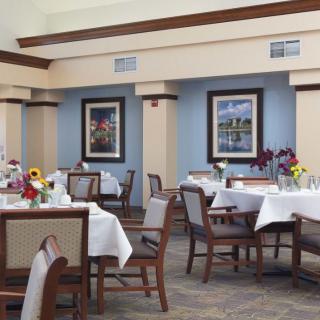 An elegant dining room with neatly arranged tables and chairs, adorned with flower centerpieces.