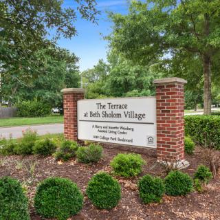 Entrance sign for The Terraces at Beth Sholom Village surrounded by greenery.