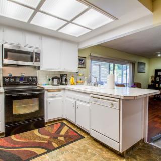 A modern kitchen with white cabinets, featuring an oven, microwave, and a countertop island.