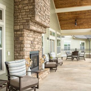 A cozy outdoor patio with comfortable seating and a stone fireplace.