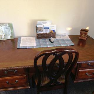A neatly organized wooden desk with a chair, showcasing office supplies and paperwork.