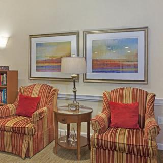 A cozy living room corner with striped armchairs and colorful wall art.