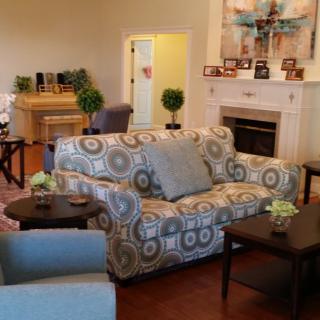A cozy living room with a patterned sofa, fireplace, and a piano.