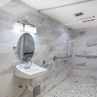 A modern accessible bathroom featuring a sink, mirror, and stylish tile design.