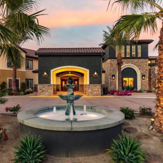 A beautiful building with a central fountain and palm trees at sunset.
