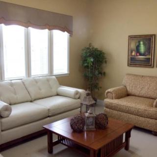 A cozy living room with two sofas, a coffee table, an indoor plant, and a painting on the wall.