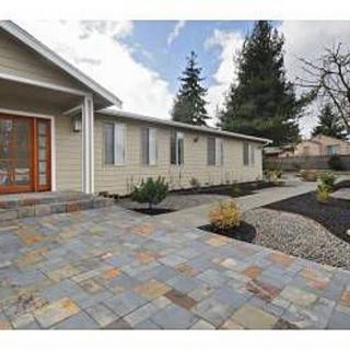 Modern home exterior with a paved walkway and landscaped front yard.