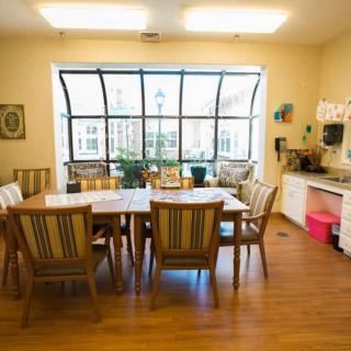 A well-lit dining area with a wooden table and matching chairs, featuring a large window that brings in natural light.