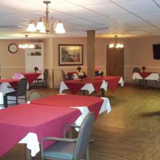 An indoor dining room with red tablecloths and arranged seating.