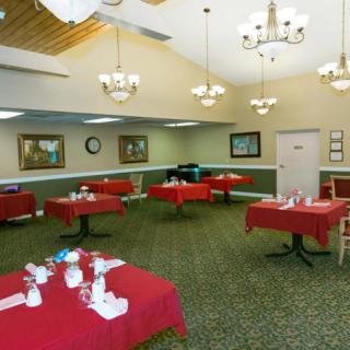 An elegant dining room with red tablecloths and chandeliers.