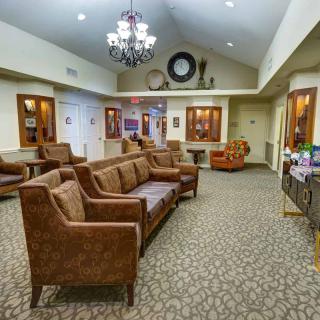 A cozy living room with brown sofas, a chandelier, and a carpeted floor.