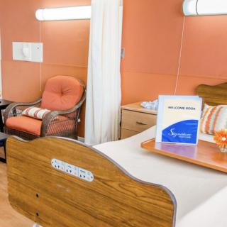 A hospital room featuring a patient bed, chair, and privacy curtains in a medical facility.