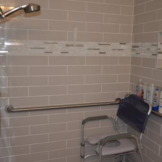 Accessible bathroom with a shower chair and grab bar.