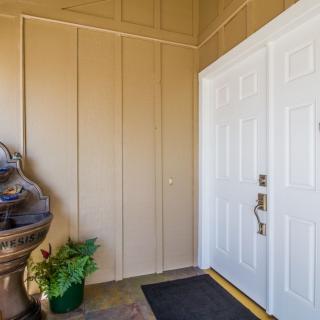 A welcoming entrance with a double door, potted plant, and decorative elements.