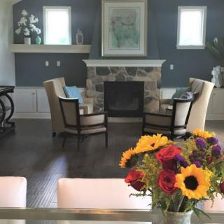 A cozy living room featuring a stone fireplace, stylish armchairs, and a vibrant bouquet of flowers.