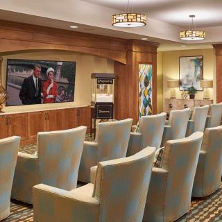 A small theater room with rows of comfortable chairs facing a large screen.