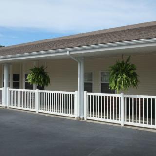 A porch with hanging plants and a white fence.