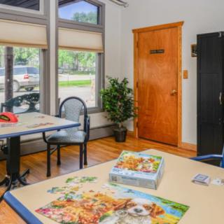 A cozy office space with desks, a plant, and puzzles on the table.