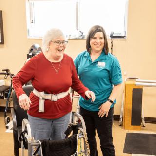 A therapist assists an elderly woman during a physical therapy session.