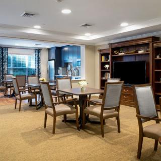 A well-furnished living and dining area with comfortable seating, a large television, and bookshelves.
