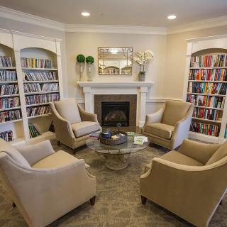 A cozy reading area with armchairs, bookshelves, and a fireplace.