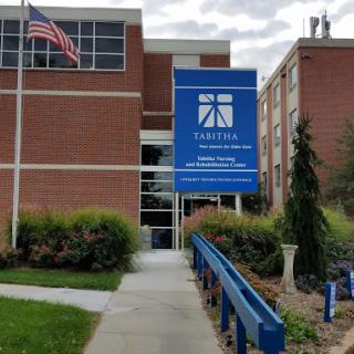 A view of a brick building featuring a large blue sign and an American flag.