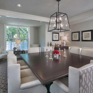 A modern dining room with a large table and elegant light fixture.