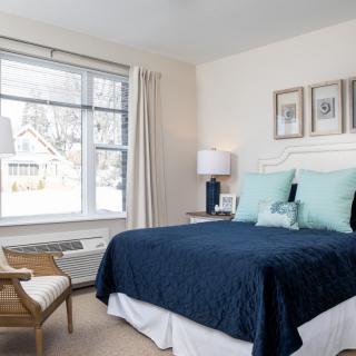 A cozy and stylish bedroom with a large window, featuring blue bedding and elegant decor.