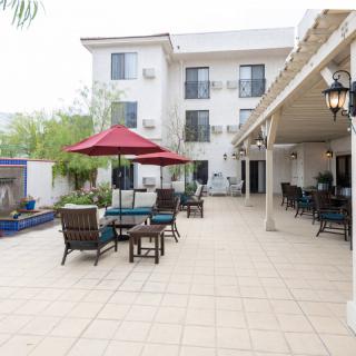 A spacious outdoor patio with tables and chairs, featuring a red umbrella and adjacent building.