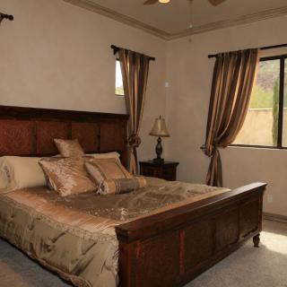 A cozy bedroom featuring a large wooden bed, elegant curtains, and a bedside lamp.