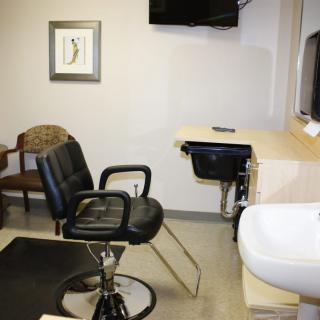 A hair salon interior with a styling chair, sink, and mirror.