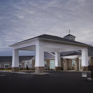 A modern building entrance with a covered driveway under a cloudy sky.