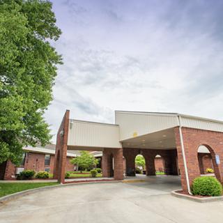 A welcoming entrance to a modern commercial building surrounded by greenery.
