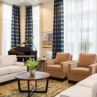 A modern living room featuring comfortable sofas and armchairs, a piano in the corner, and elegant decor.