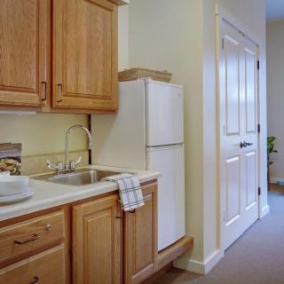 A compact kitchen area with wooden cabinets, a sink, and a white refrigerator.