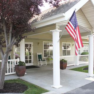 A cozy house with a front porch adorned with an American flag and patio chairs.